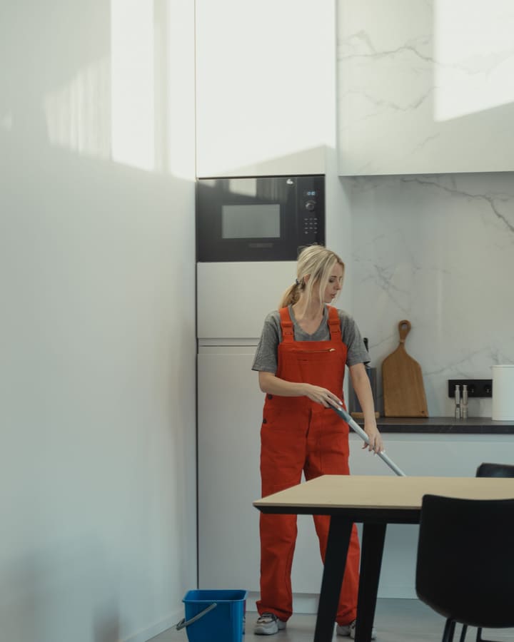 Operatrice di Elite Cleaning in divisa pulisce il pavimento di una cucina a Trento